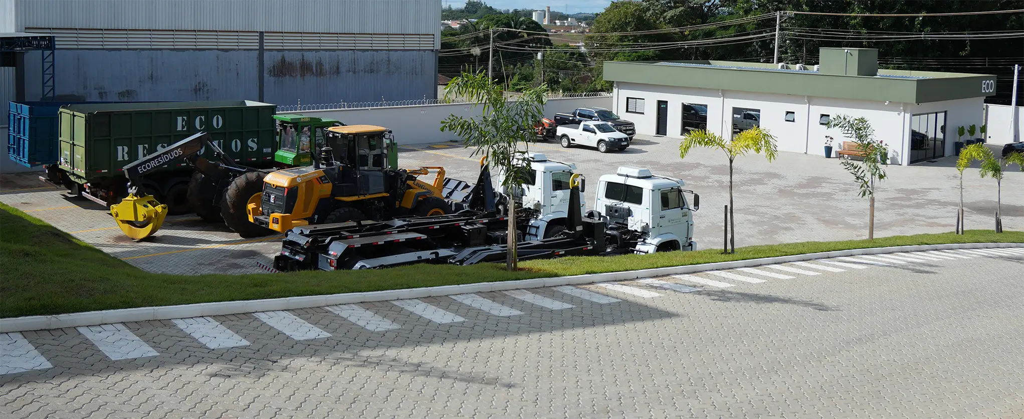 Pátio da EcoResíduos com caminhões, tratores, máquinas florestais e caçambas utilizados em operações de biomassa, cavaco de madeira e erradicação de plantações.