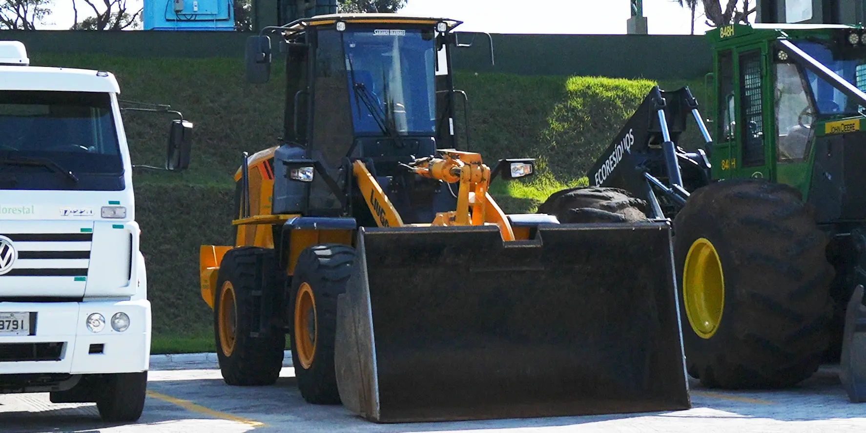 Pá-carregadeira, trator e caminhão da EcoResíduos utilizados no manejo, carregamento e transporte de cavaco de madeira e resíduos de biomassa.